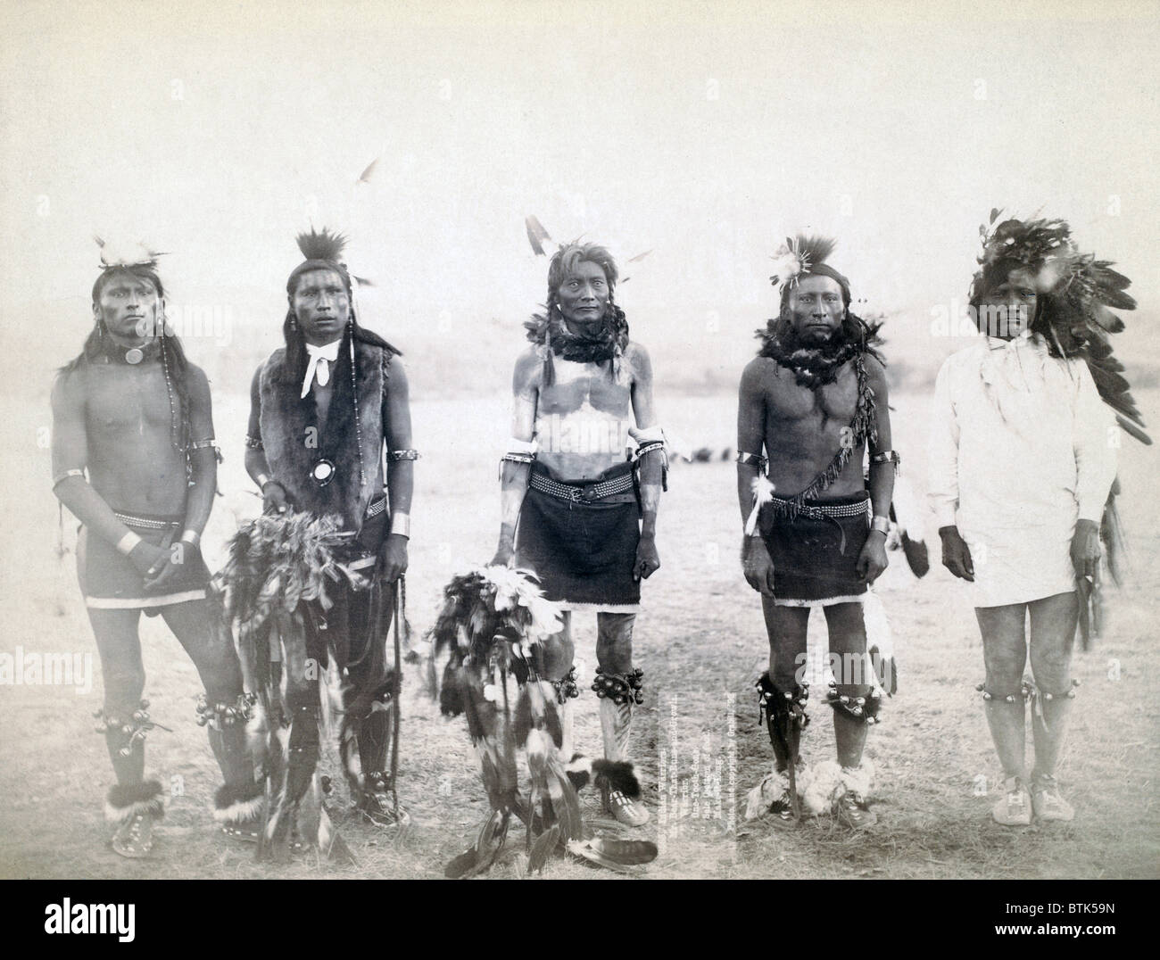 Five Grass dancers in ceremonial clothing. Mr. Bear-that-Runs-and-Growls, Mr. Warrior, Mr. One-Tooth-Gone, Mr. Sole (bottom of foot), Mr. Make-it-Long, at a Grass Dance on or near Cheyenne River Reservation, South Dakota. Photo by John C. Grabill. 1890 Stock Photo