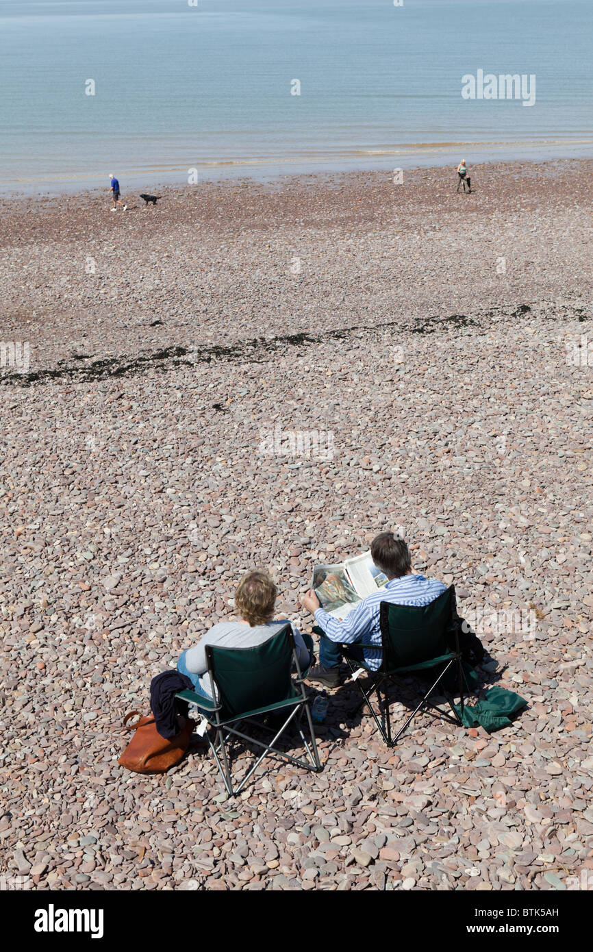 Couple reading on the beach at Watchet, Somerset Stock Photo