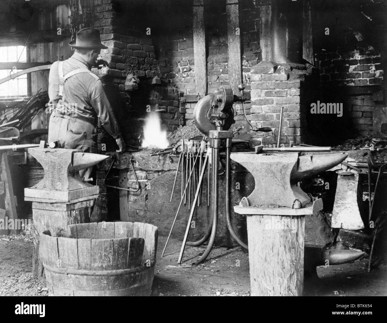 Occupational portrait of a blacksmith, in his smithy with anvils, ca. 1906 Stock Photo