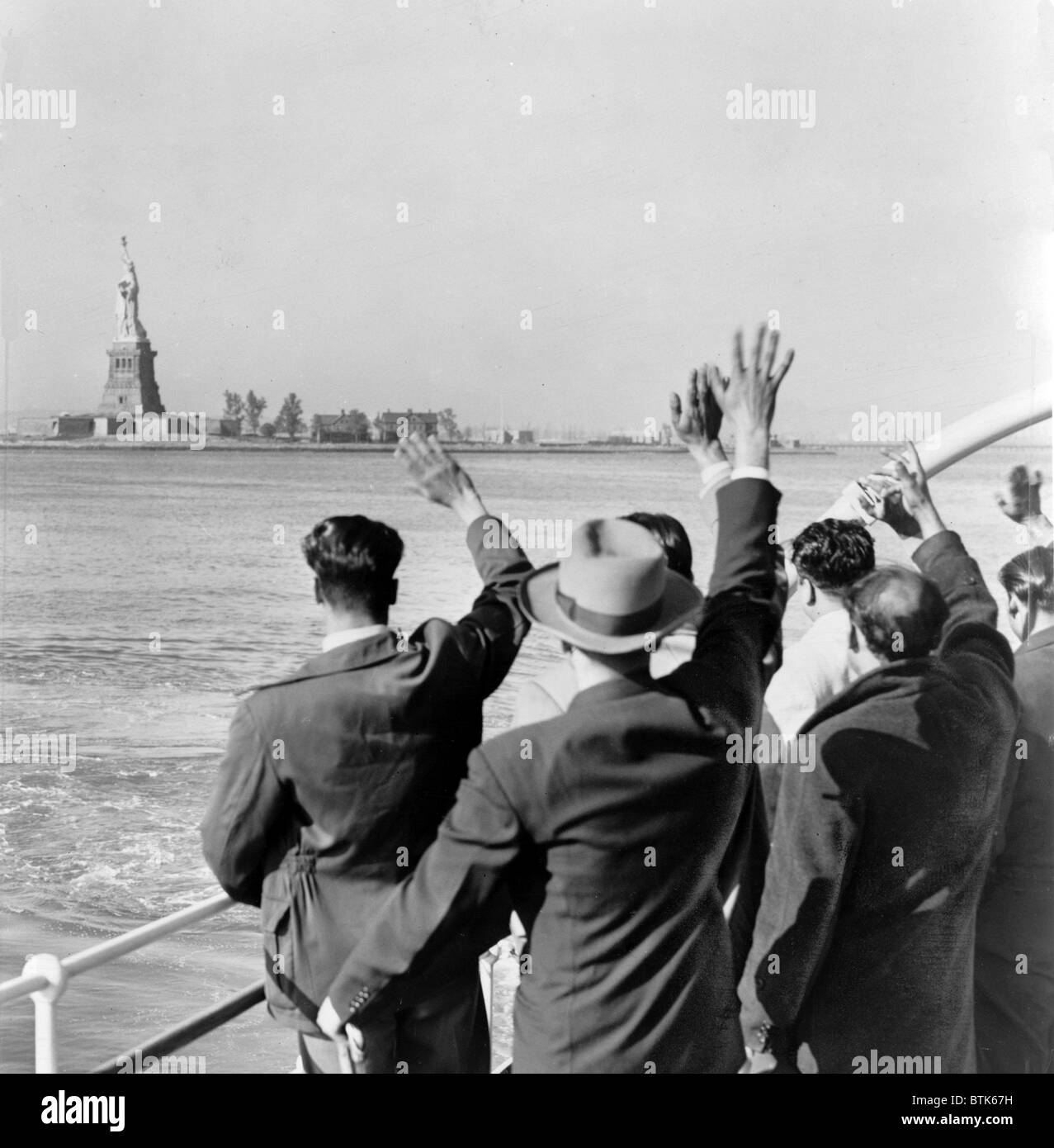 Statue of Liberty. Part of a group of 171 illegal immigrants wave goodbye to the Statue of Liberty from the Coast Guard cutter that took them from Ellis Island to the Home Lines ship Argentina in Hoboken for deportation. 1952 Stock Photo