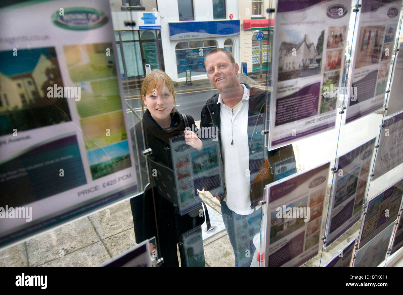 Young couple looking at houses in estate agents window Stock Photo
