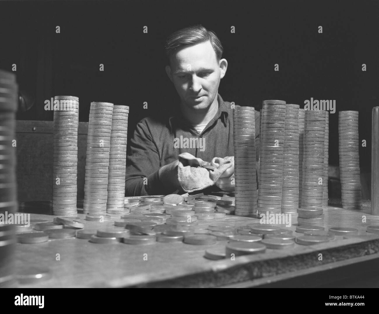 Circular blanks of copper and crass inspected for flaws in metal structure before they become shell casings for the U.S. in World War II. Chase Copper and Brass Company, Euclid, Ohio, 1942. Stock Photo