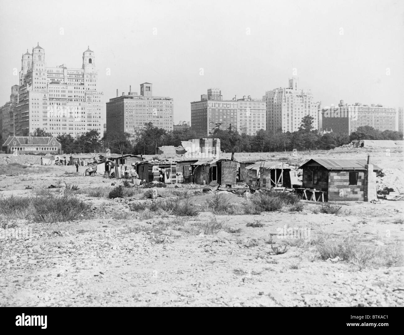 Squatter's shacks in Central Park with the landmark Dakota Apartment  building in the background. The Hooverville grew up at a construction site  where work was suspended due to New York City's Depression, image size:1300x1077