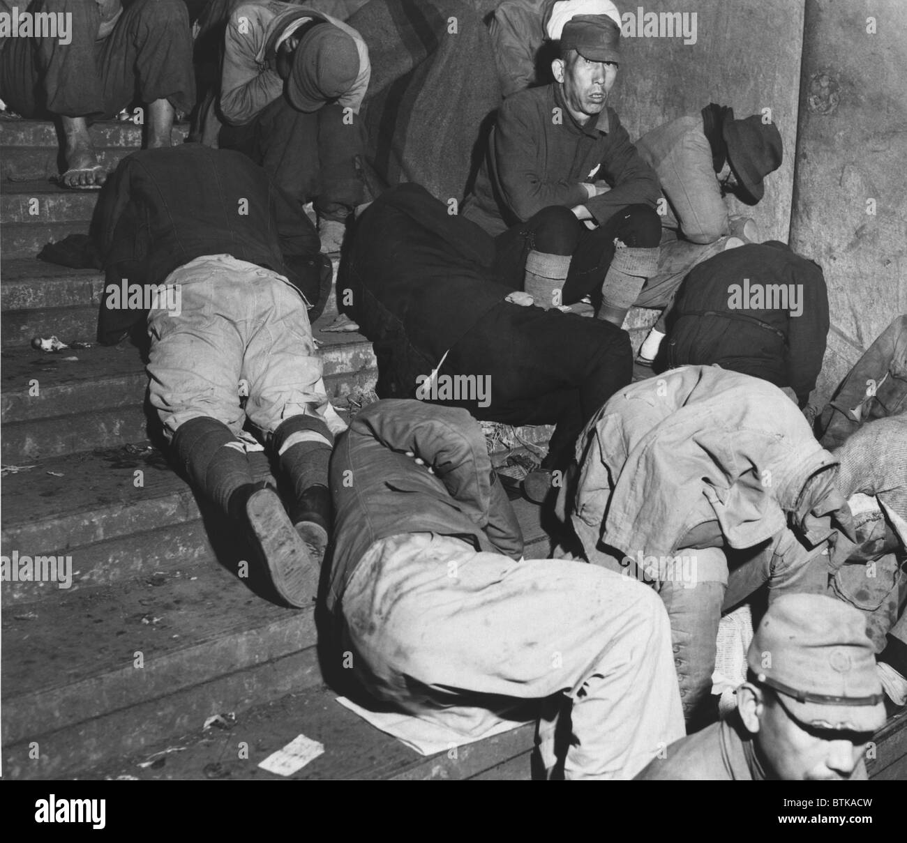 Homeless Japanese in Tokyo, months after Japan's World War II surrender, spend the night on the steps of one of Tokyo's subway stations. Many discharged soldiers are still wearing their military uniforms. Dec. 6, 1945. Stock Photo