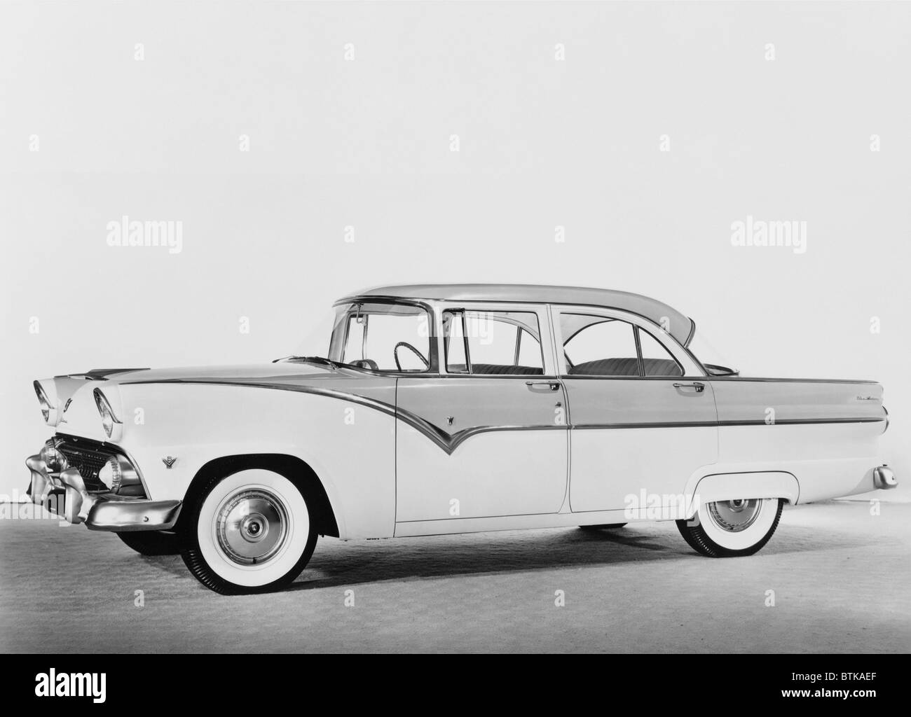 1955 Ford four-door sedan featured two-tone paint, heavy chrome detail, white wall tires, wrap around windshield, and a hint of Stock Photo