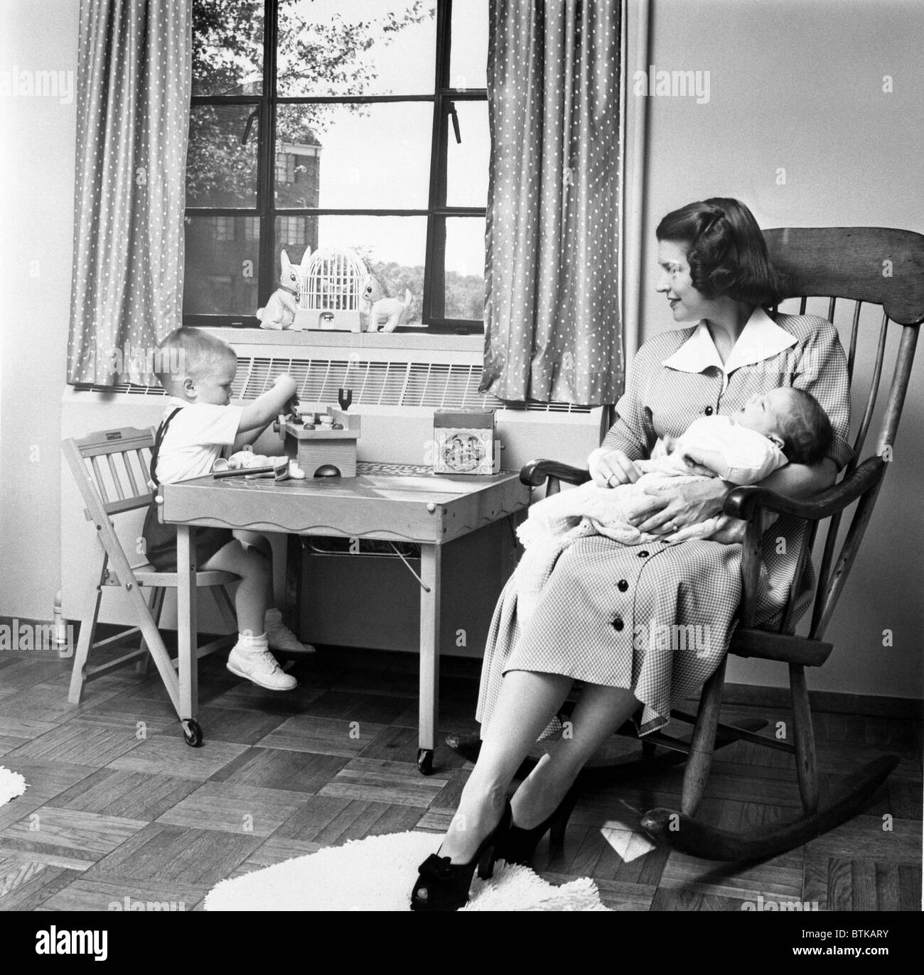 Future First Lady in 1952.  Betty Ford holds her second son, Jack, while her eldest son Michael plays at a small table in their Stock Photo