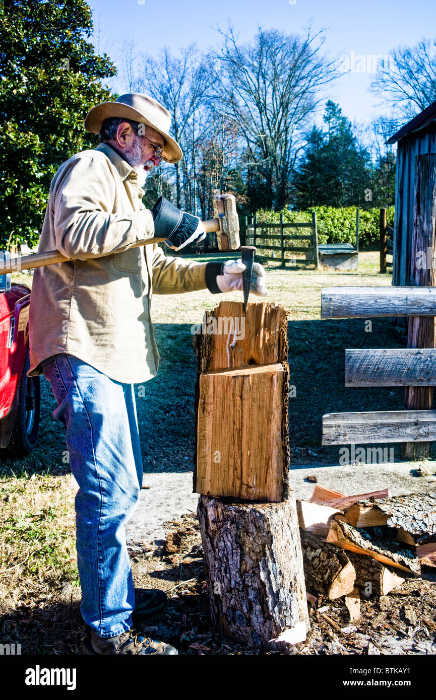 SOUTH CAROLINA, YORK Farmer using a wedge and mallet to split logs for