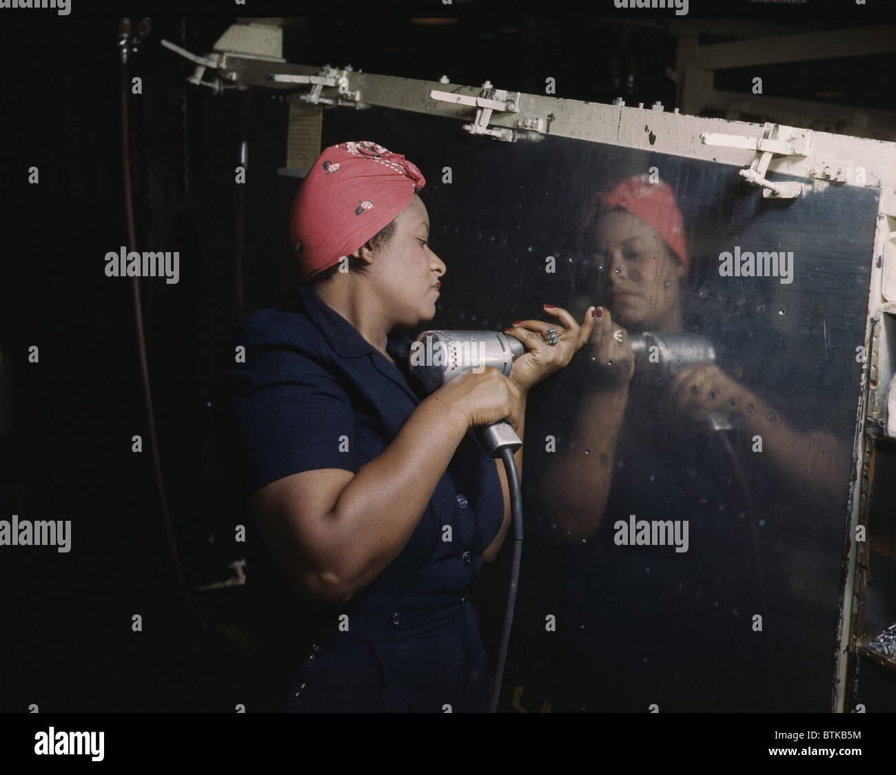 An African American Rosy the Riveter, operating a hand drill at Vultee-Nashville, while working on a 'Vengeance' dive bomber, at Vultee-Nashville, Tennessee defense plant. 1943. Black leaders negotiated hard with the Roosevelt administration to ban discrimination by defense contractors in the World War II defense industries. Stock Photo