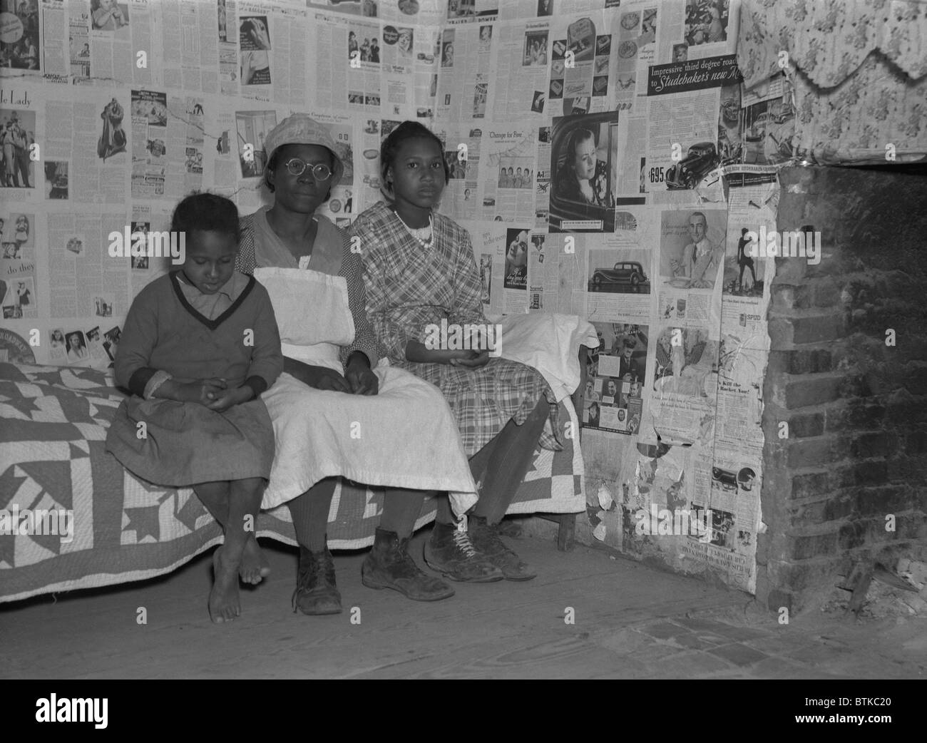 African American mother with her two daughters living in primitive conditions as plantation tenants in Gees Bend, Alabama. They are descendants of slaves that worked the same land before the Civil War. April 1937 photo by Arthur Rothstein. Stock Photo