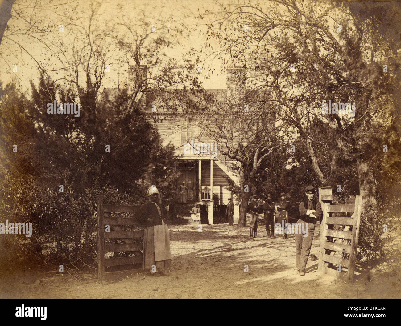 A newly liberated female slave and Union soldiers stand in at the entrance to the captured plantation of the General Thomas F. Drayton, Hilton Head Island, South Carolina. Photo by Henry P. Moore, a photographer traveling with the Union forces, May 1862. Stock Photo