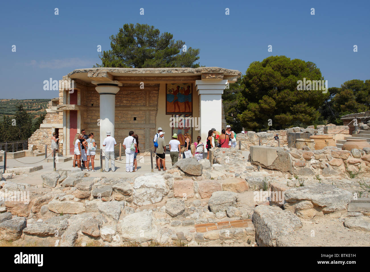 Tourists looking at the famous mural 'Rhyton Bearers' located at the South Propylaeum of the ancient Knossos Palace. Crete, Greece. Stock Photo