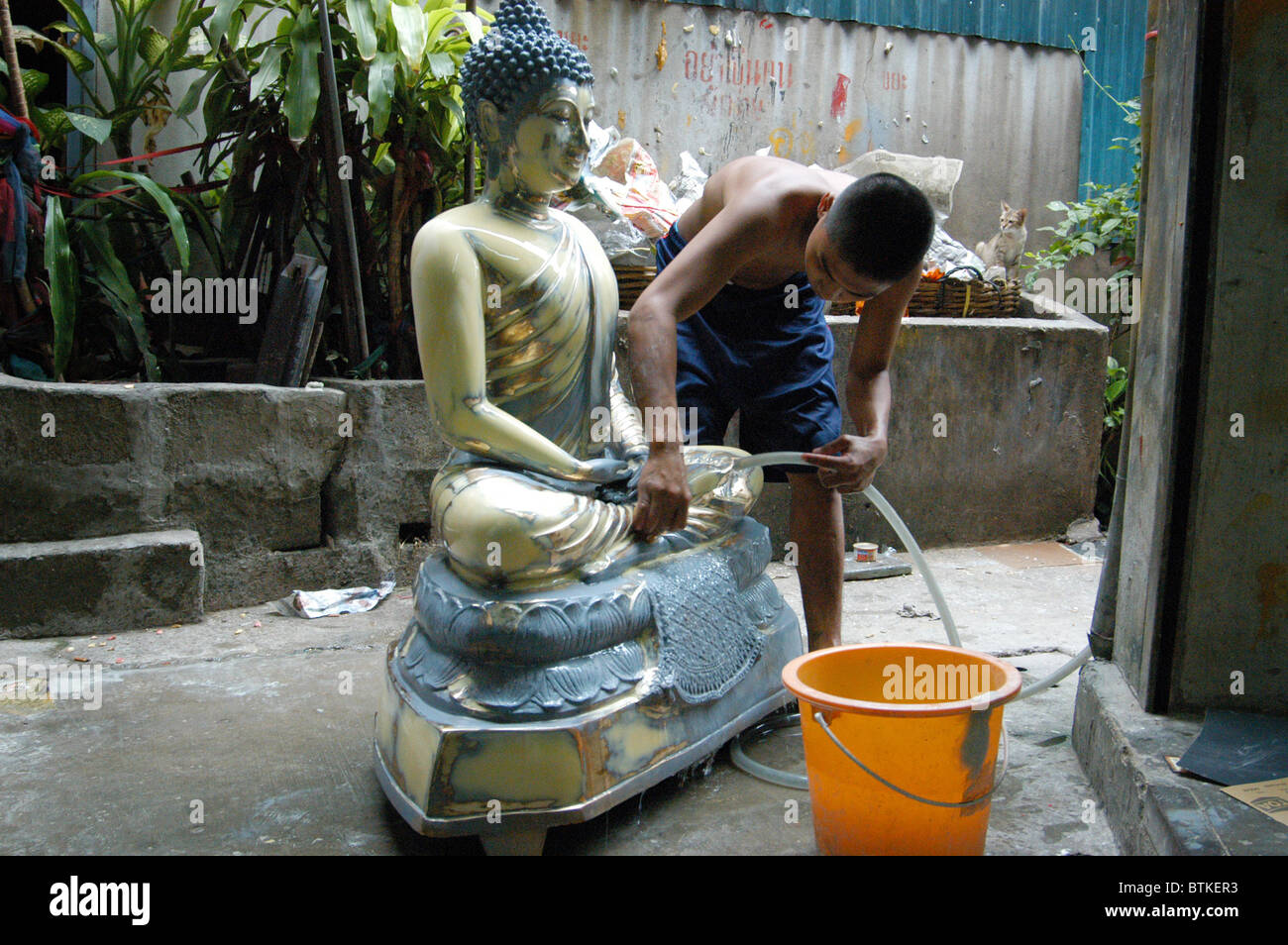 Boy cleans Buddha outside buddha workshop. Stock Photo