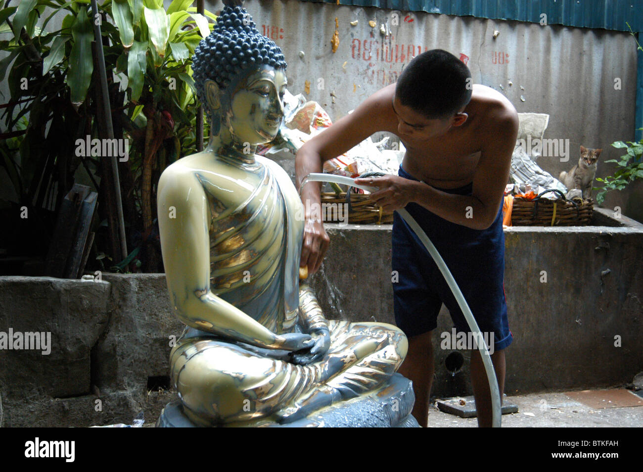 Boy cleans Buddha outside buddha workshop. Stock Photo