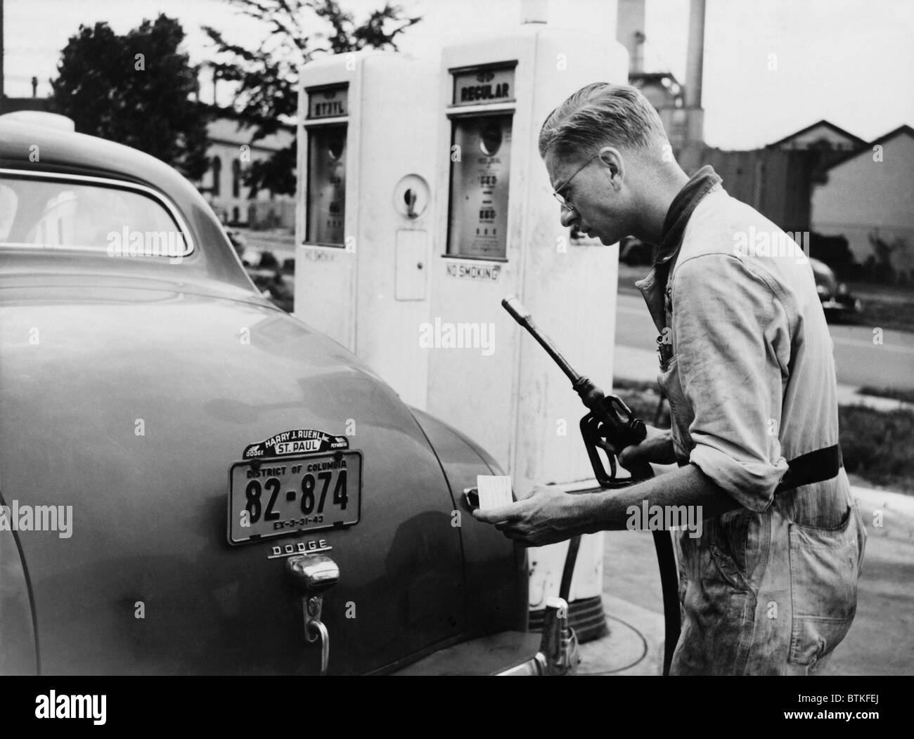 An automobile service station attendant measures out gasoline in accordance with the World War II gasoline rationing. July 1942. Stock Photo