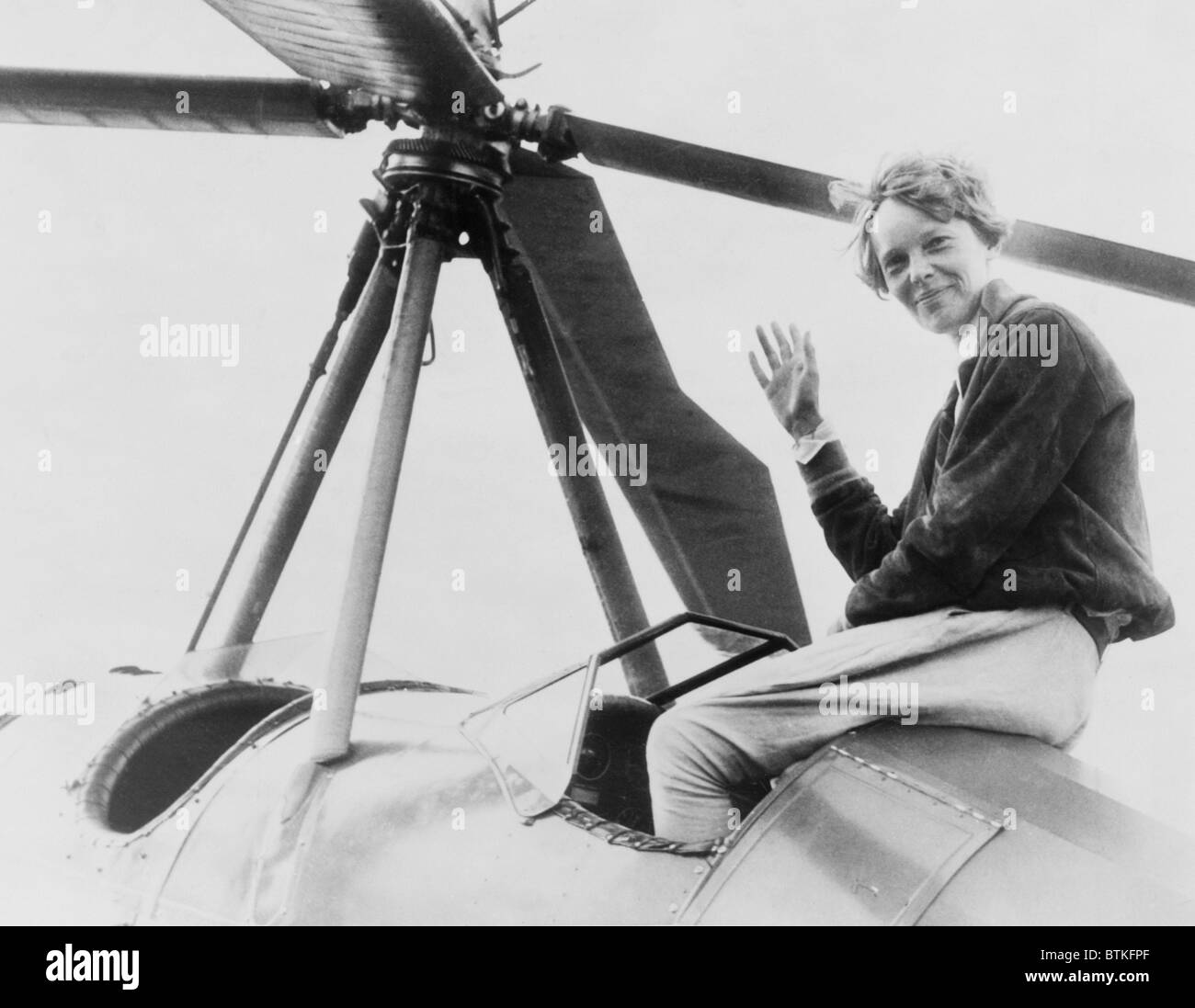 Amelia Earhart (1897-1937), waving, seated outside cockpit on top of an Autogiro, in Los Angeles, shortly after she became the first woman to complete a solo coast-to-coast flight. August 1932. Stock Photo