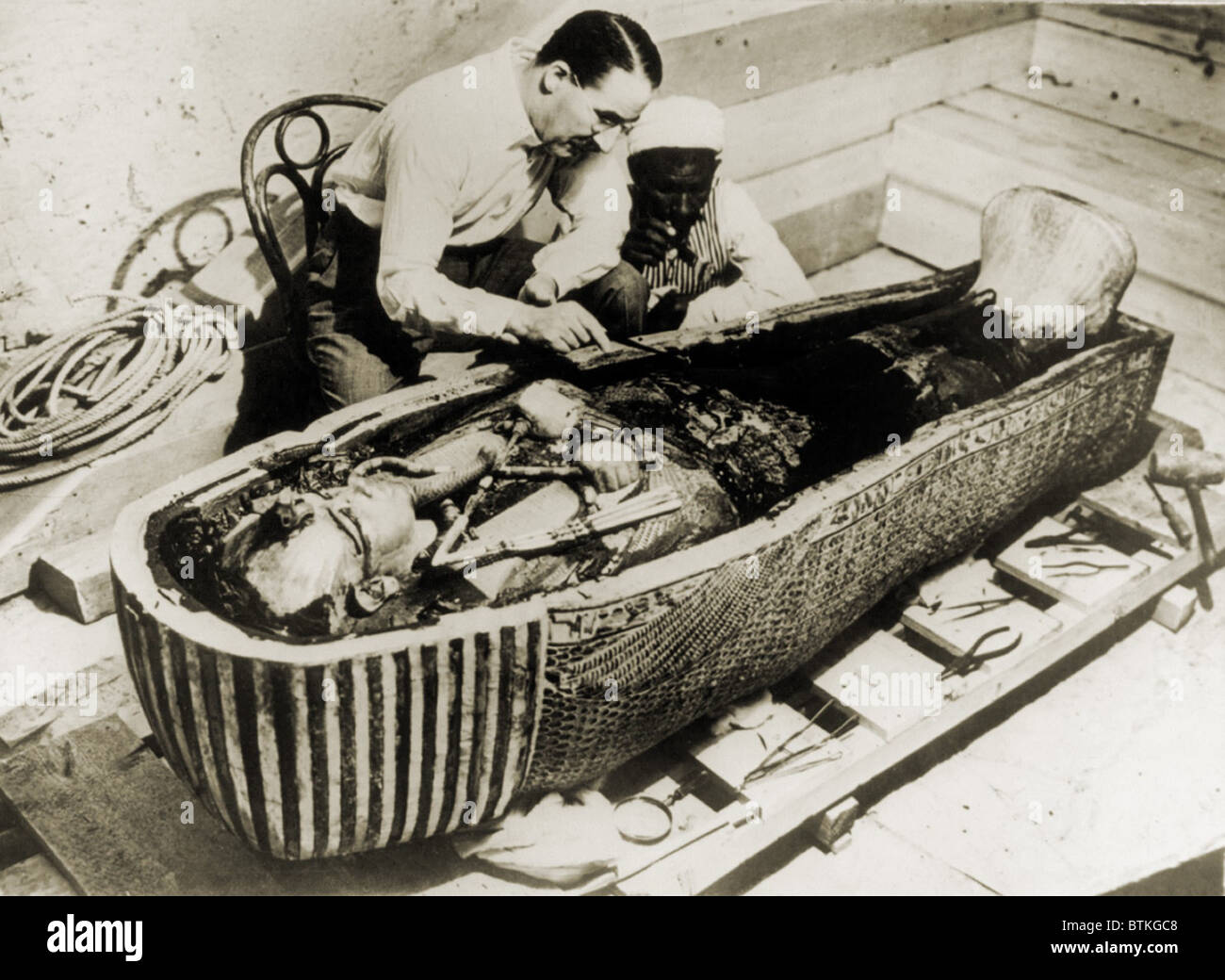 Howard Carter (1873-1939), seated beside coffin of King Tutankhamen, removing the consecration oils which covered the third or innermost coffin. 1926 Stock Photo