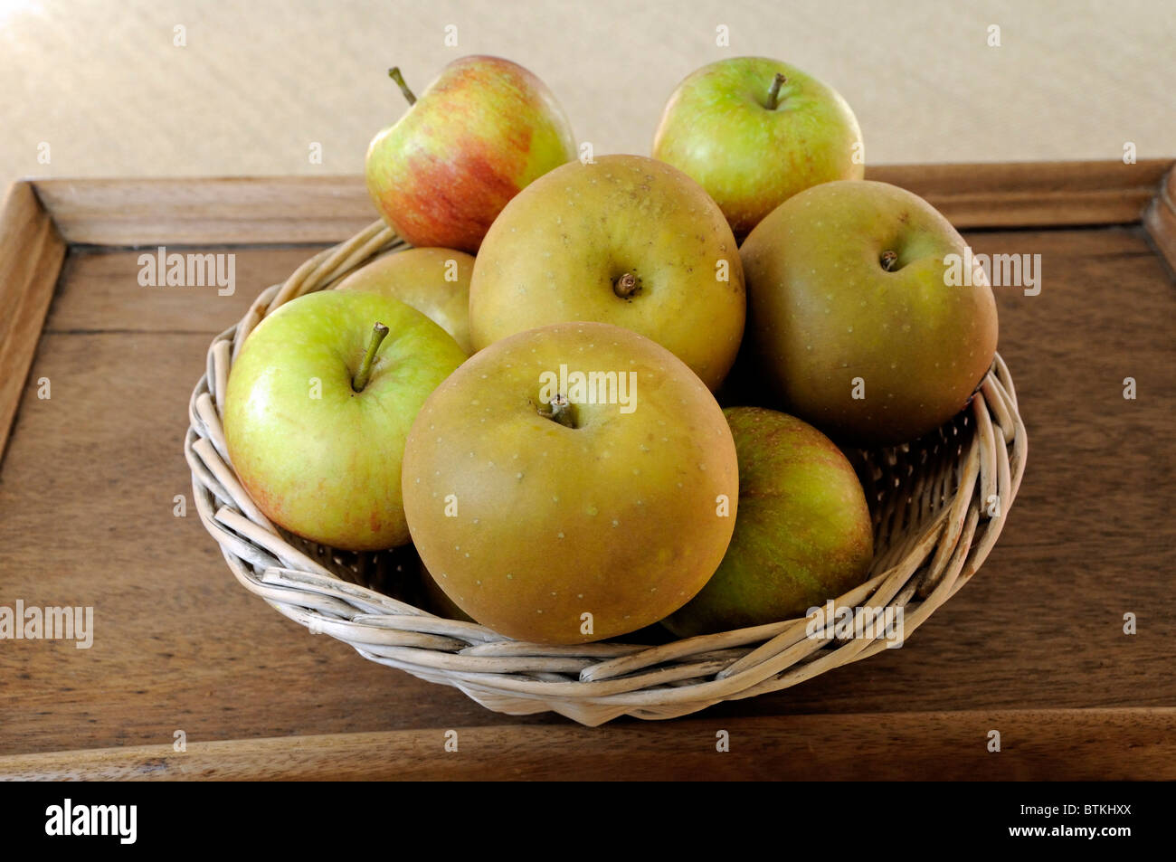 Basket of Egremont Russet and Cox apples on old wooden tray Stock Photo