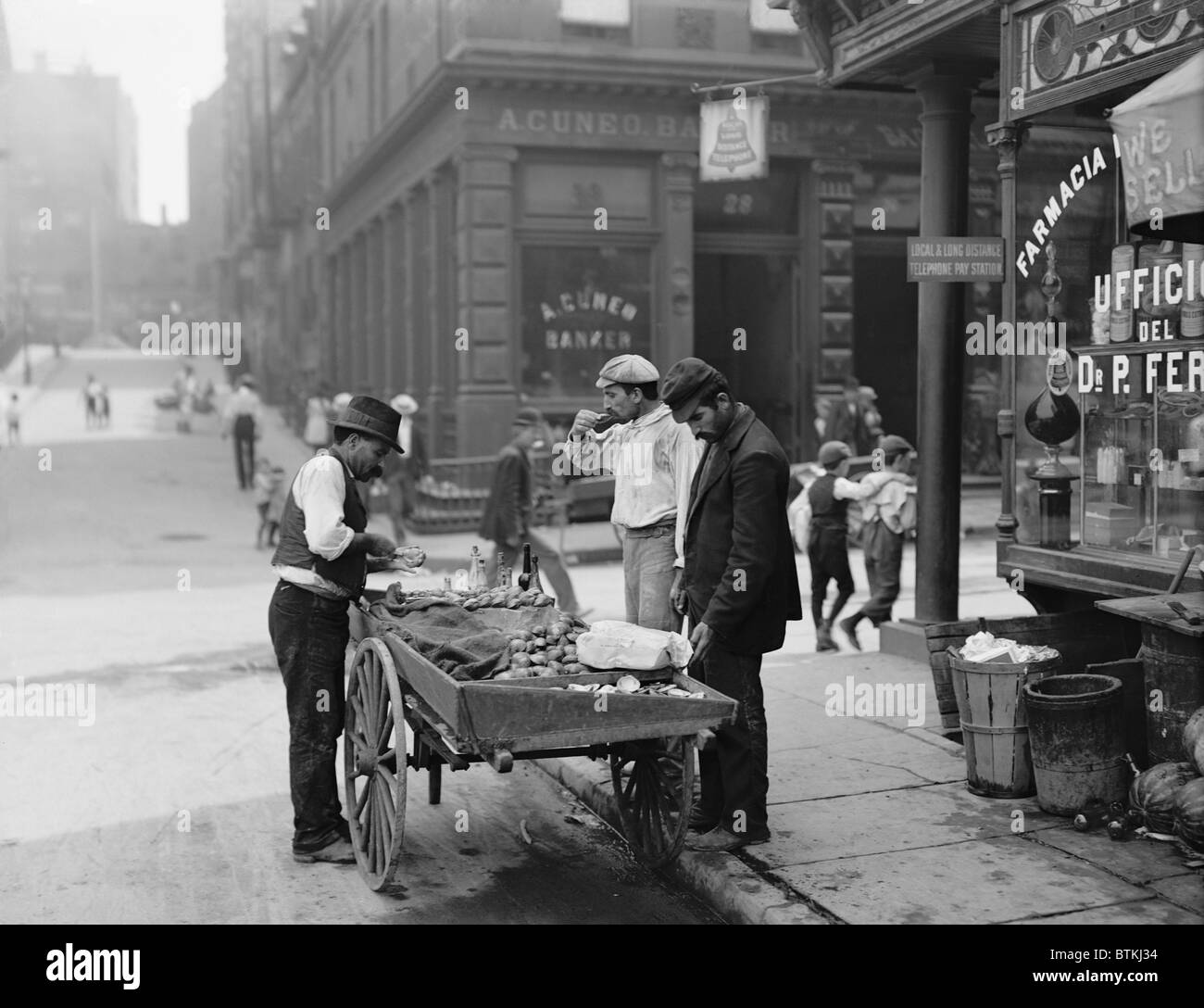 Men eating fresh clams from a pushcart peddler in the Italian neighborhood of Mulberry Bend in New York City. Ca. 1900 photograph by Byron. Stock Photo