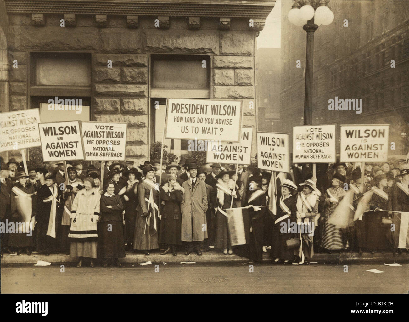Crowd of women's suffrage supporters demonstrating with signs reading, 'Wilson Against Women,' in Chicago on October 20, 1916. Wilson withheld his support for Votes of Women until 1918. Stock Photo