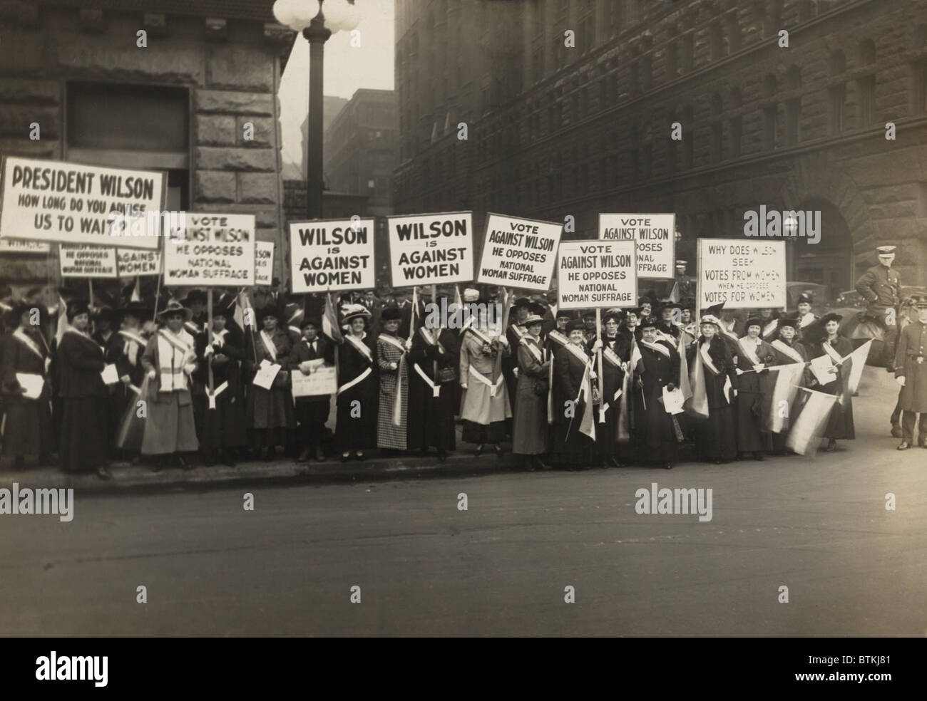 Crowd of women's suffrage supporters demonstrating with signs reading, 'Wilson Against Women,' in Chicago on October 20, 1916. Wilson withheld his support for Votes of Women until 1918. Stock Photo