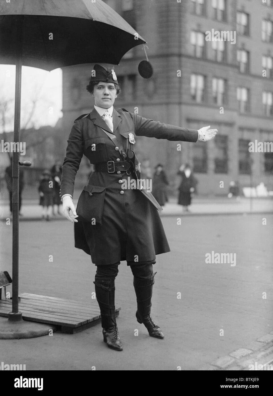 Policewoman directing traffic in Washington, D.C. in 1918. Her progressive uniform combines knee high boots, below knee pants, and a knee length jacket. During the First World War, women filled many men's jobs. Stock Photo