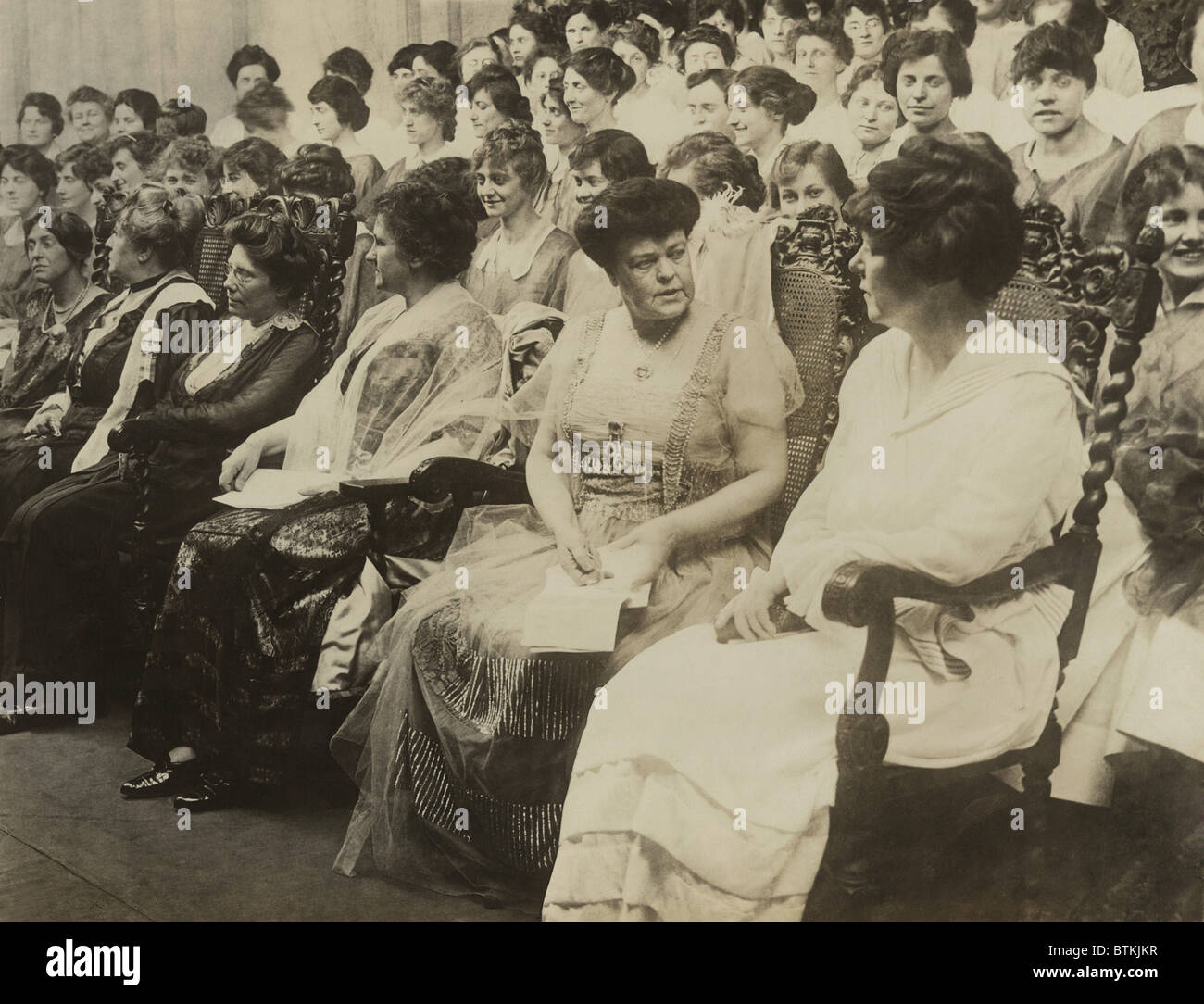 Alva Belmont, seated second from right, was the wealthy former wife of a Vanderbilt and Belmont, and the most important financial benefactor of the National Woman’s Party. Dripping in jewels, she attends the Women's Voter Convention, Sept. 1915. Stock Photo
