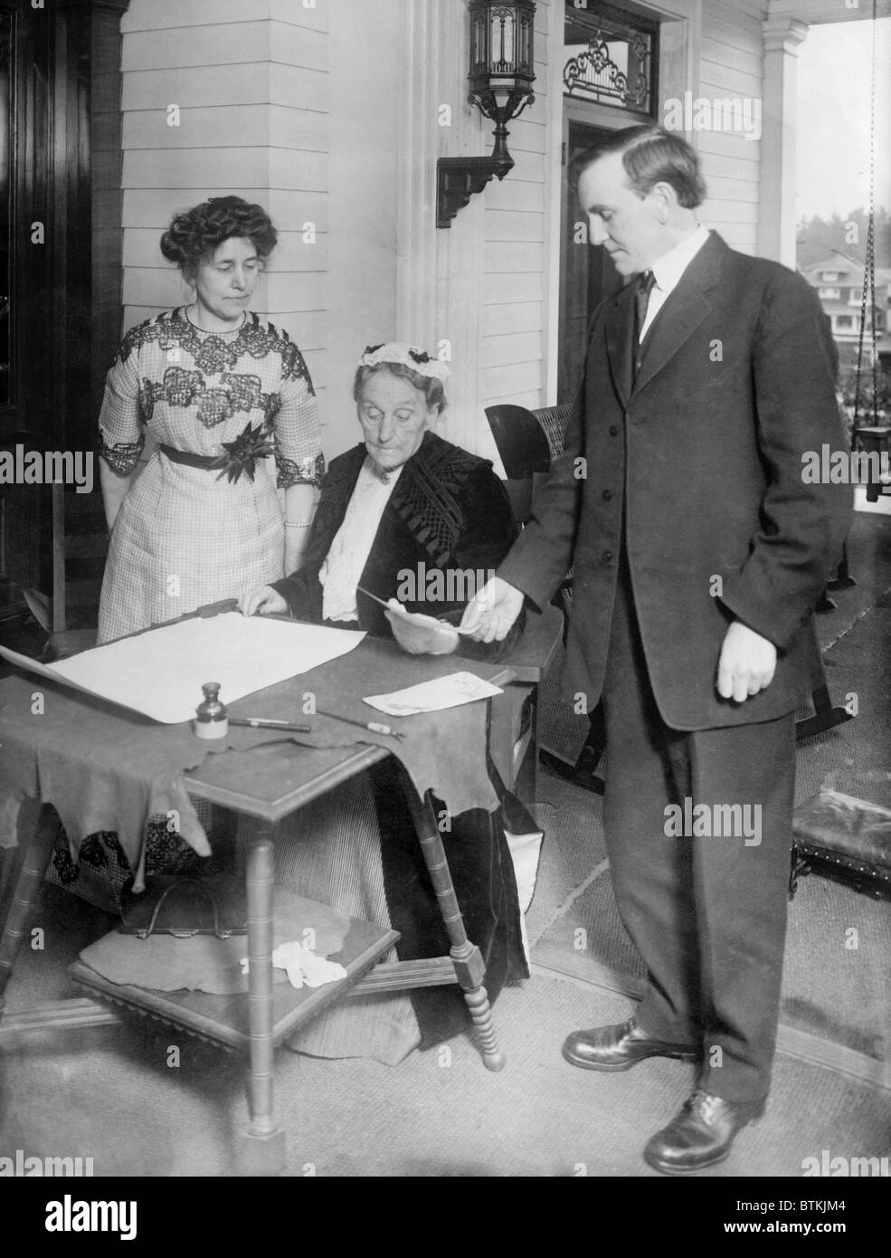Abigail Scott Duniway (1834-1915), Oregon publisher and women's rights advocate, signing Oregon's Equal Suffrage Proclamation on Nov. 30, 1912, while Governor Oswald West and Viola M. Coe look on. Stock Photo