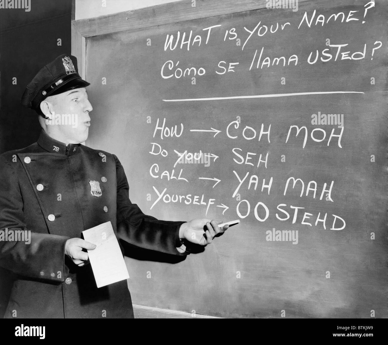 New York Police Officer Richard Perry practices basic Spanish phrases using phonetic syllables written on blackboard. Ca. 1955. Stock Photo
