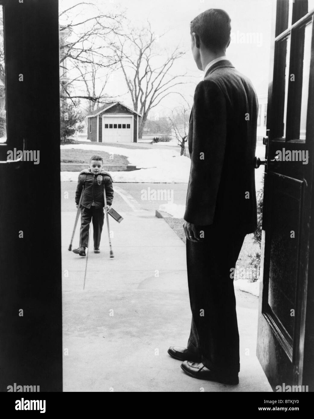 School principal, E. Joseph LaLiberte, waits for seven-year-old polio victim, Eddie Randolph in 1956. 1950s discovery of polio vaccines ended the devastation of the crippling disease. Stock Photo