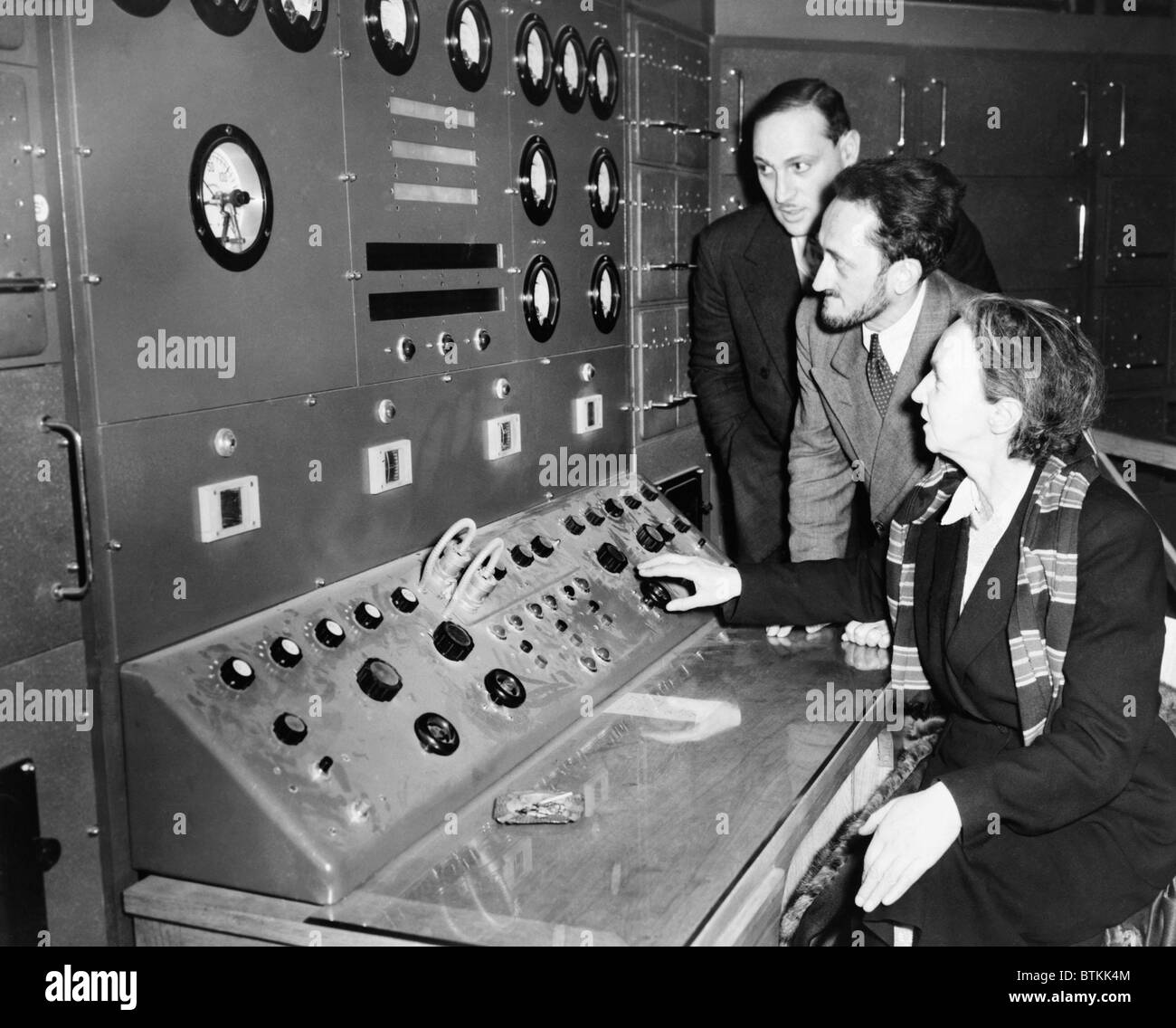 Atomic scientist Irene Curie (1897 -1956), operating the controls of France's first nuclear reactor at Chatillon, a Parisian suburb in 1948. Fellow physicists, Maurice Surdin (1911-2003) and Jean Perrin (1870-1942) look on. Stock Photo