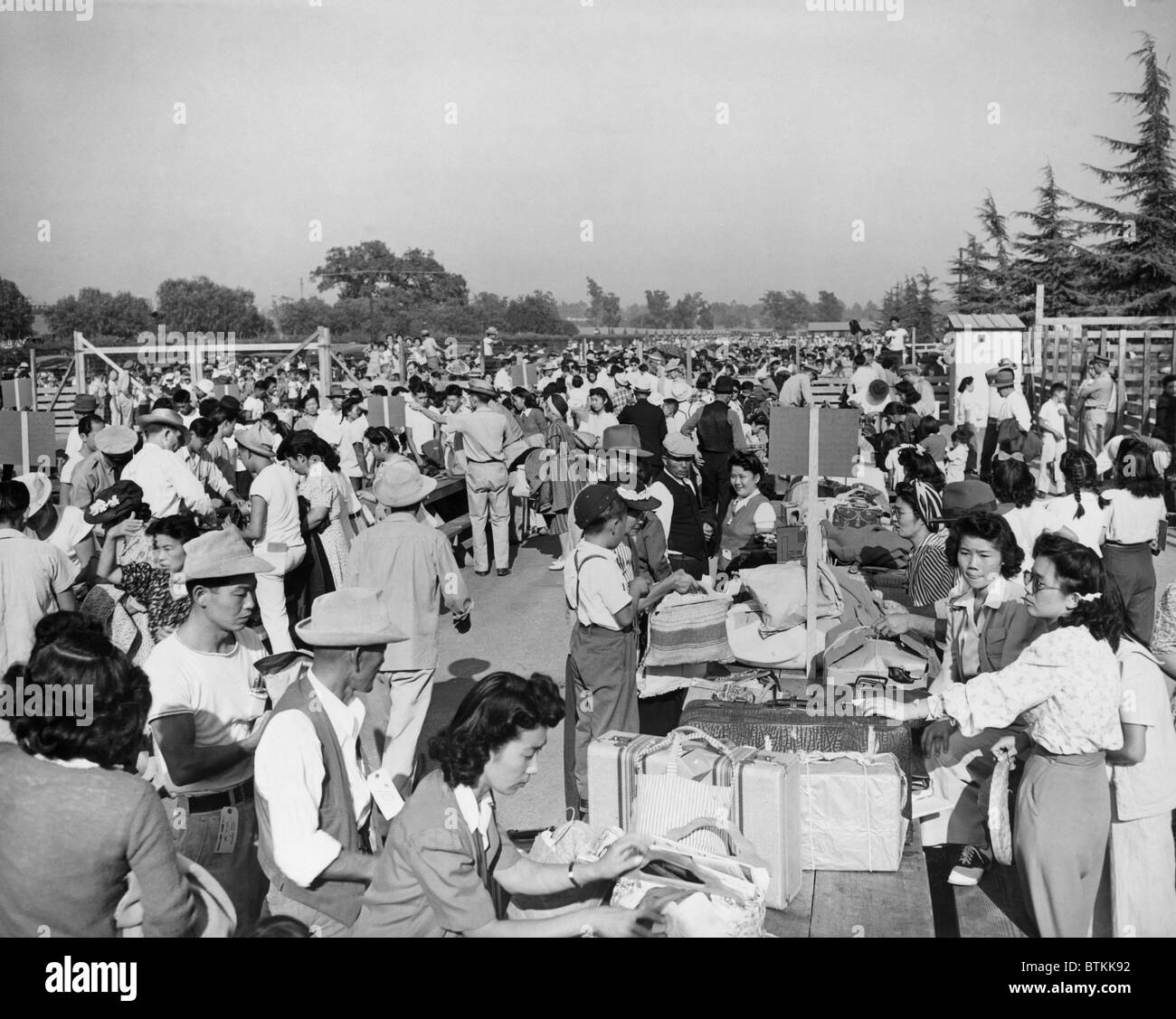 Japanese-Americans at the Santa Anita Assembly Center where family groups identify their baggage prior to departure to the relocation camps that would be their homes for the duration of World War II. 1942. Stock Photo