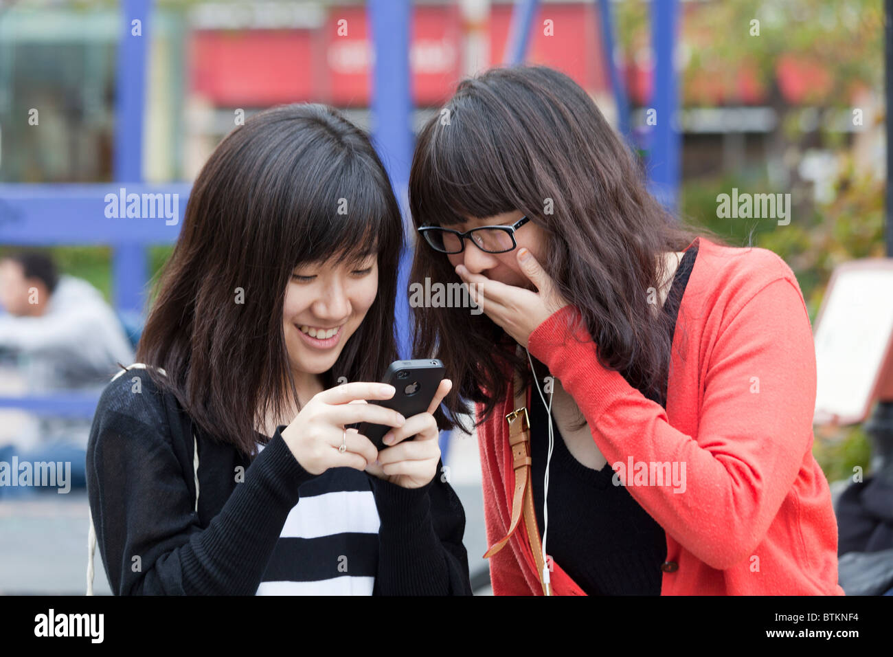 Asian tourist photographing with iPhone 4 in John F. Kennedy Plaza, Philadelphia, Pennsylvania, USA Stock Photo