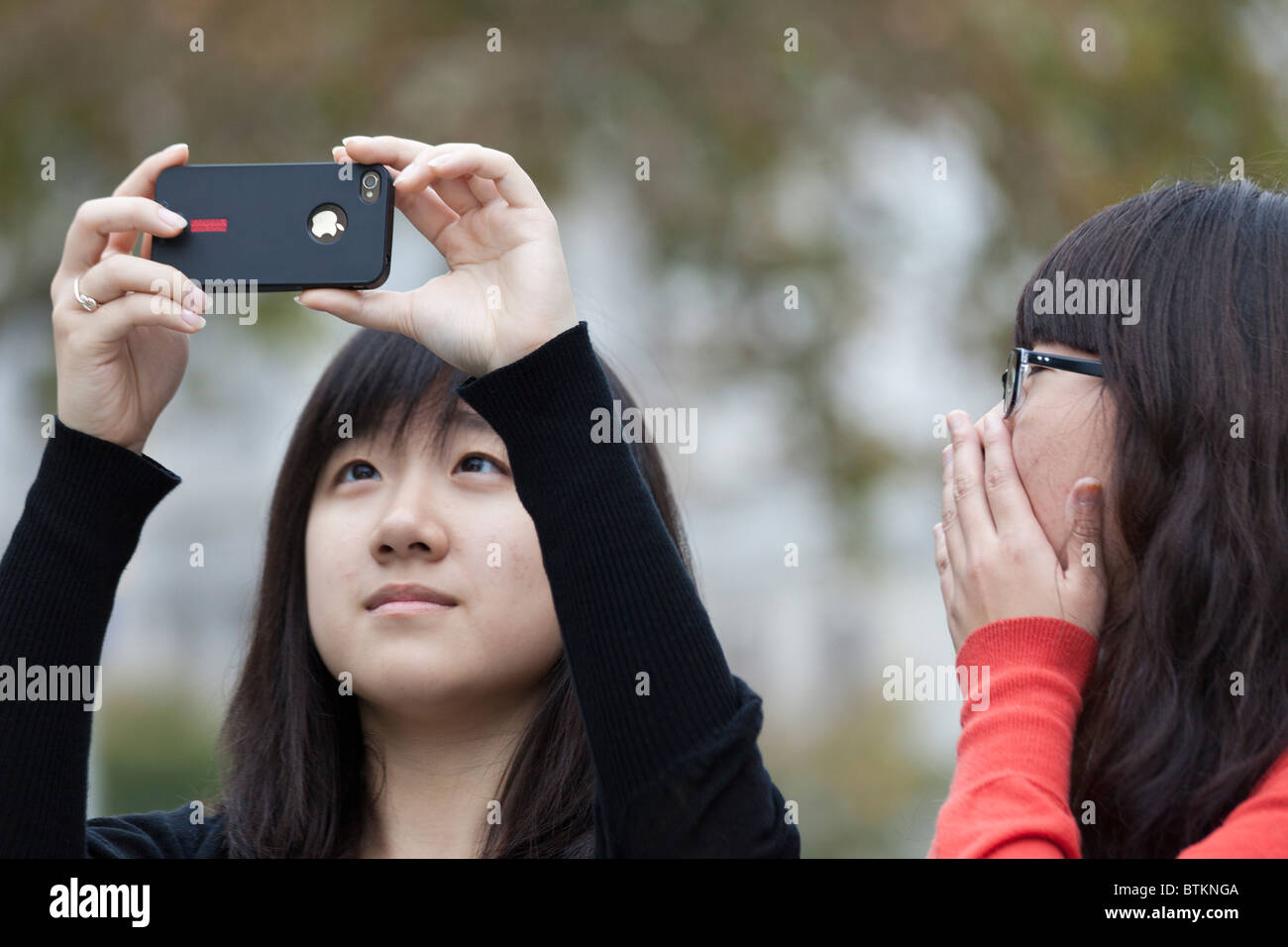 Asian tourist photographing with iPhone 4 in John F. Kennedy Plaza, Philadelphia, Pennsylvania, USA Stock Photo