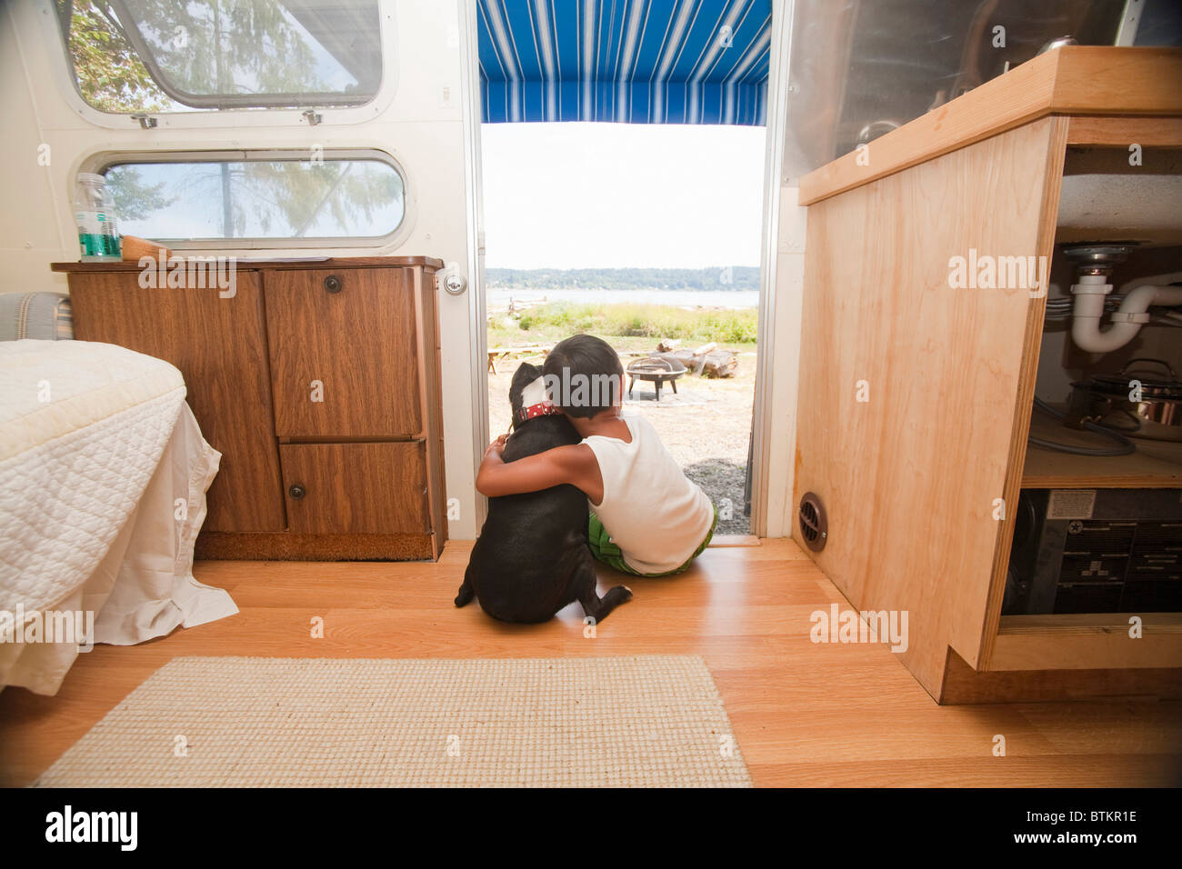 boy and dog sitting in camper doorway Stock Photo