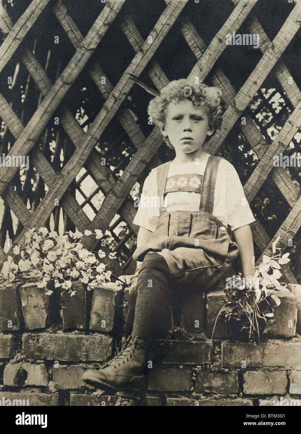 Historical photo (1910) of a boy sitting on a wall Stock Photo