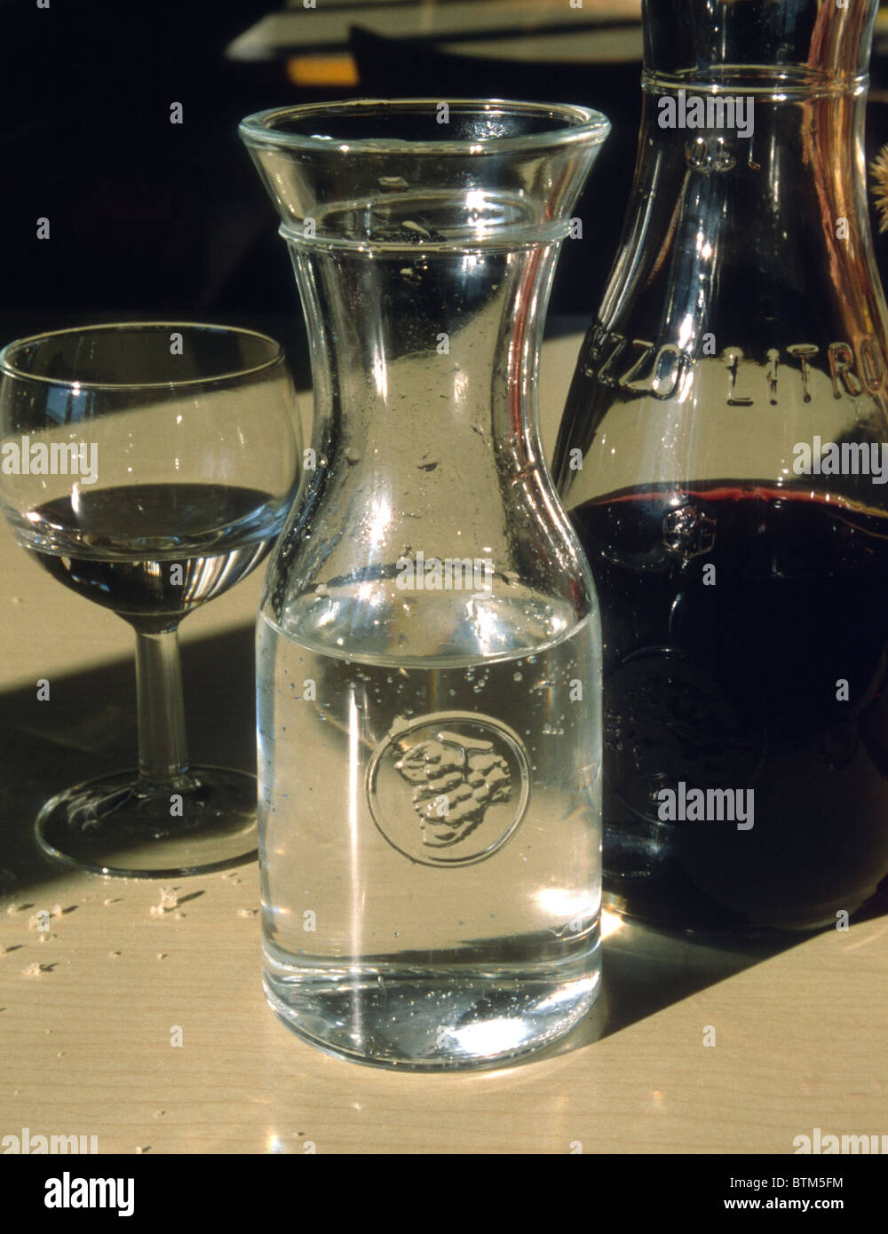 A carafe of water, a wineglass with water, and a carafe of red wine outside a small restaurant in northern Italy Stock Photo