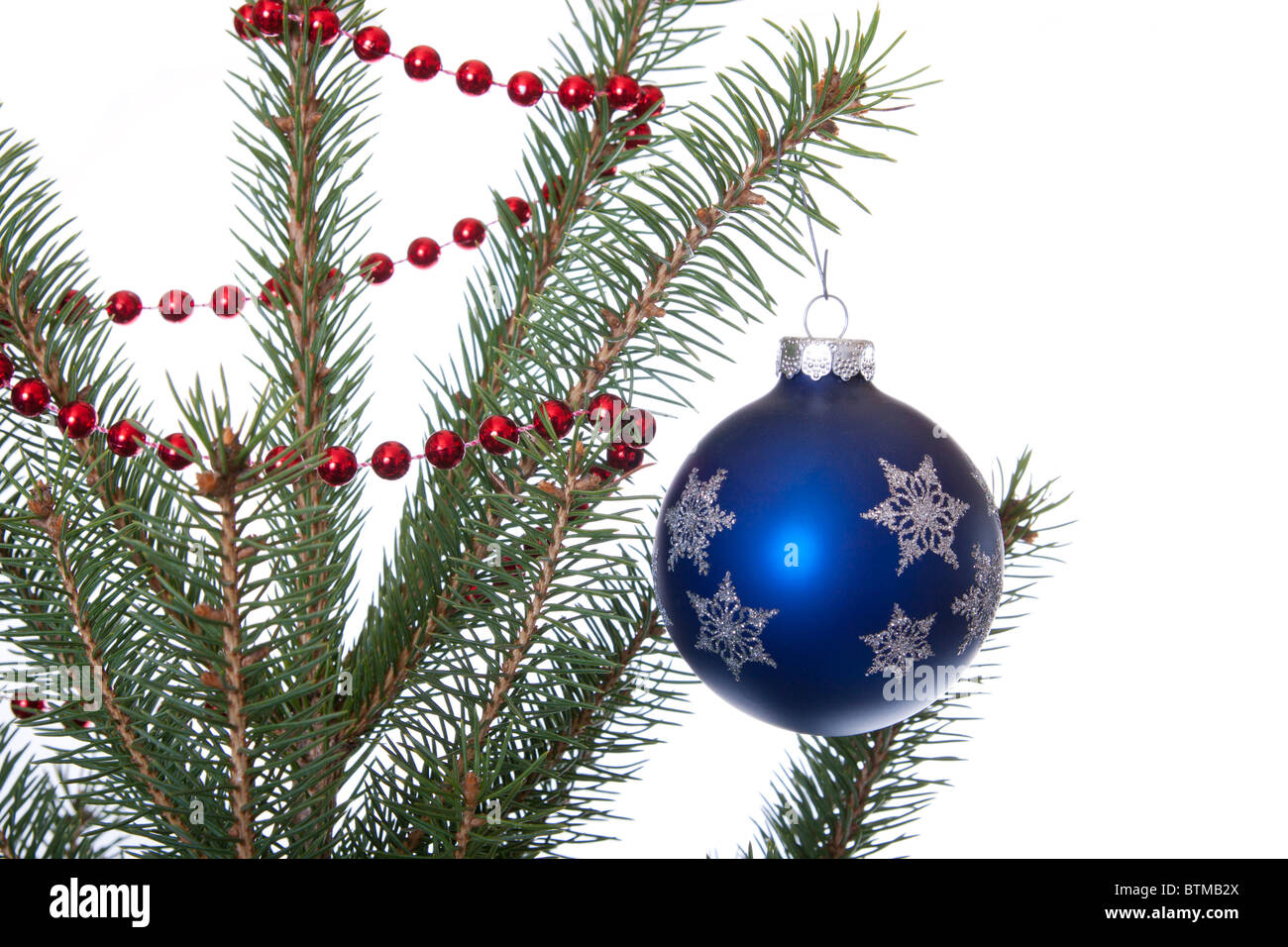 blue orb christmas ornament hangs on a christmas tree with garland on white Stock Photo