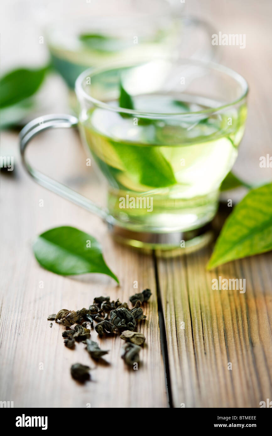 closeup of dry green tea, and a cup with fresh green tea. in the background, out of focus cup with fresh tea Stock Photo