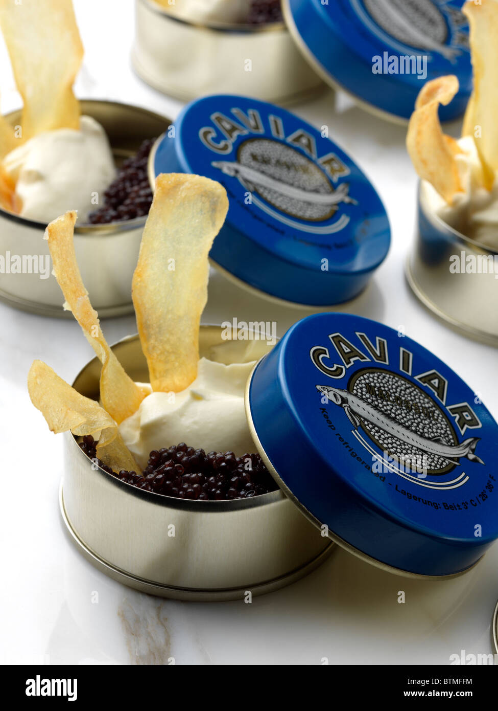 Individual portions of caviar in tins with game chips Stock Photo