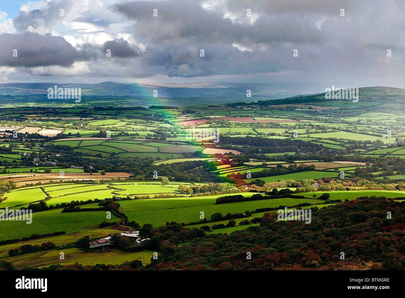 A rainbow arcs over the landscape from a viewpoint on Bodmin Moor, Cornwall. The hills of Dartmoor, Devon, in background. Stock Photo
