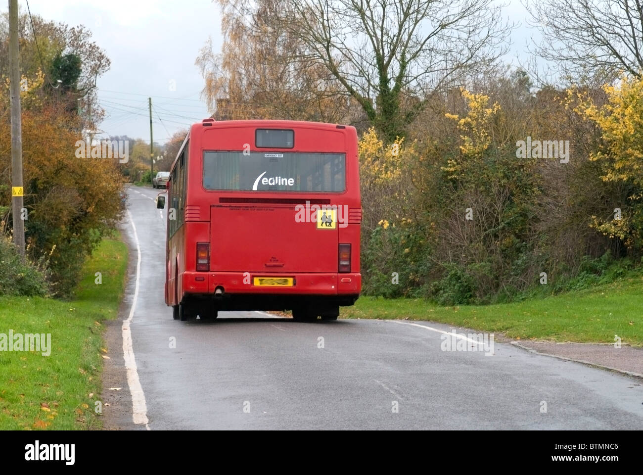 Red School Bus traveling through Village Stock Photo