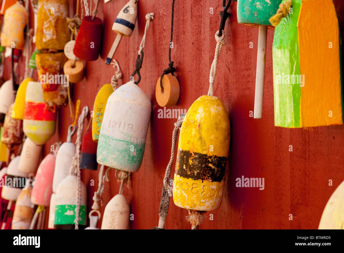 Lobster Pot Buoys hang on the wall of a building along the wharf in Bar Harbor, Maine USA Stock Photo