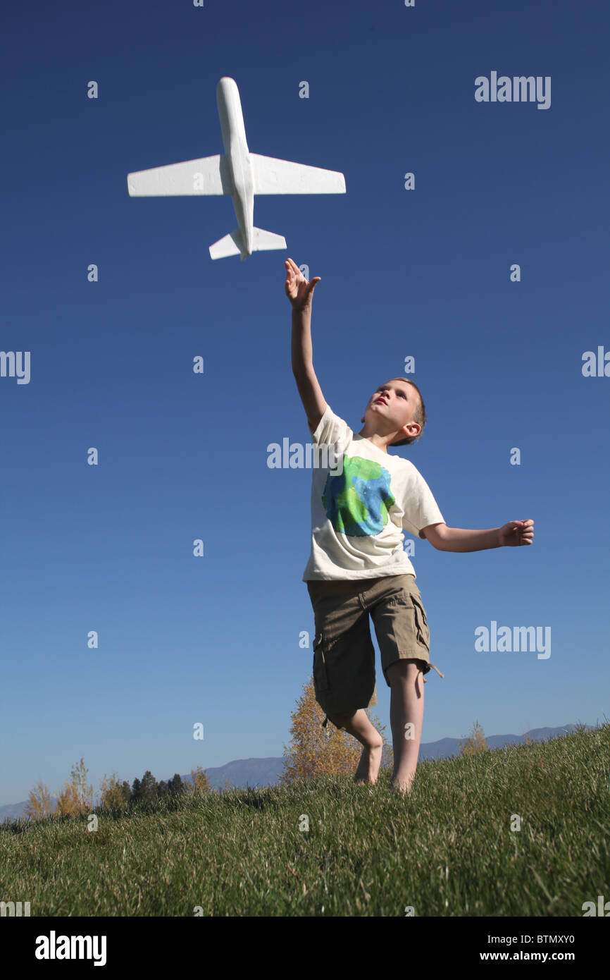 yhappy oung boy throwing toy airplane into the air Stock Photo