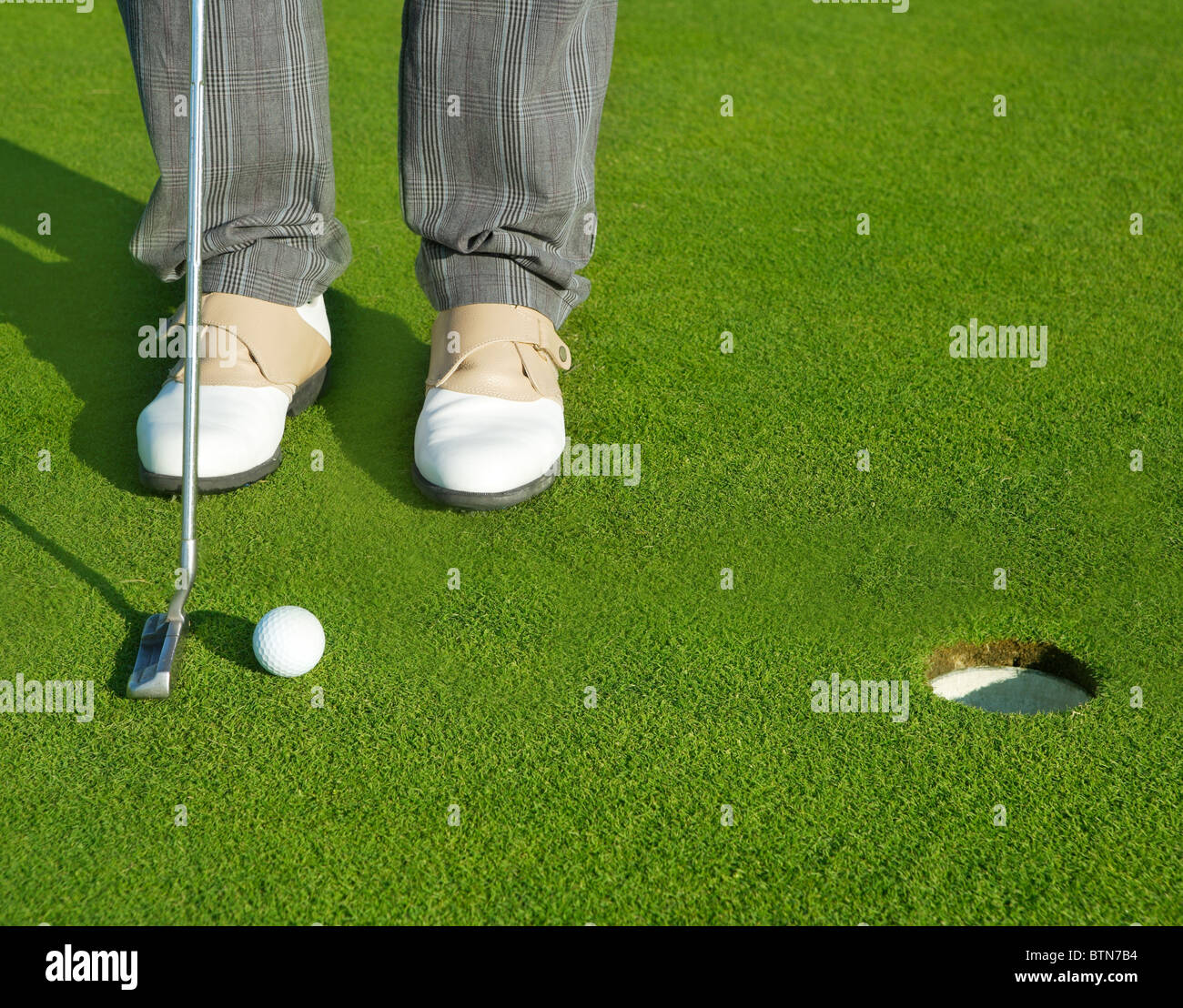 Golf green hole course man putting ball inside short putt Stock Photo