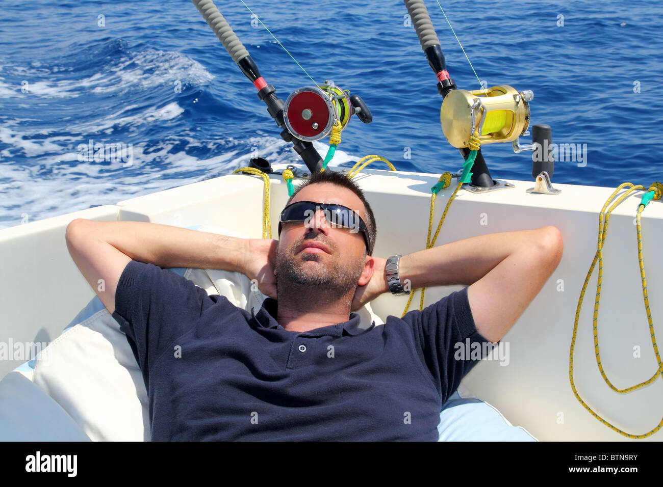 Sailor man fishing resting in boat summer vacation blue sea Stock Photo