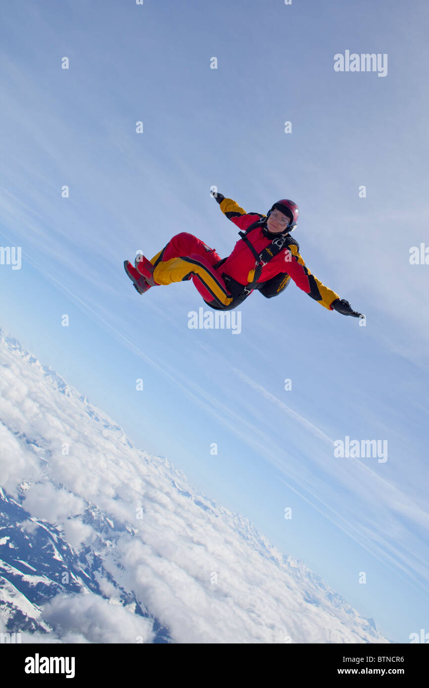 Skydiver girl is flying head up within the sit fly position over a ...