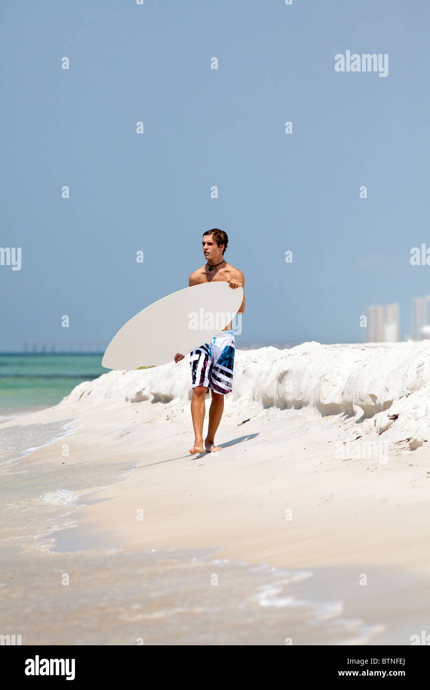 Young man carries a skimboard at Panama City Beach, Florida Stock Photo