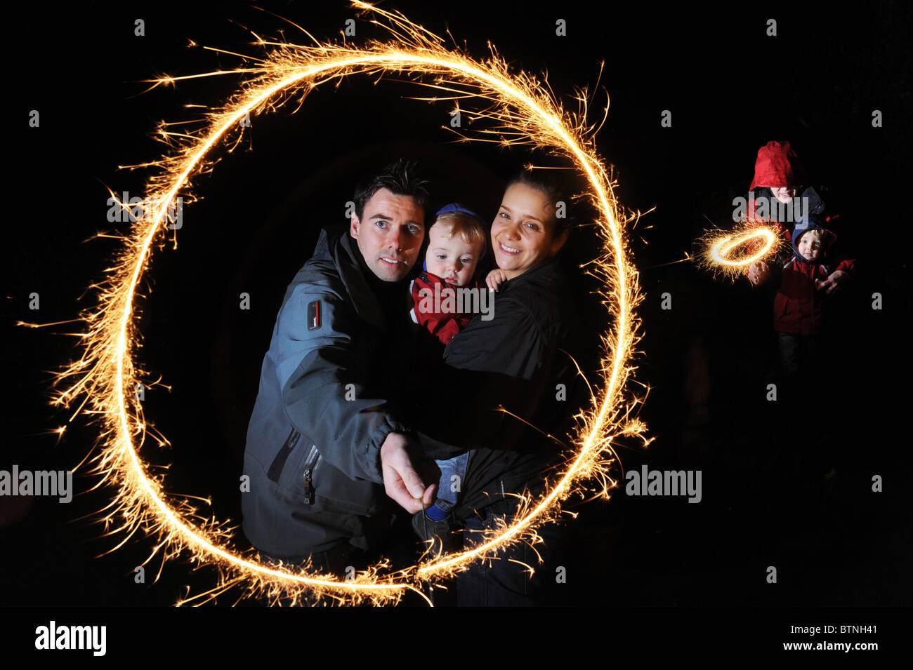 Family fireworks night Young couple and child with sparkler on bonfire night Stock Photo