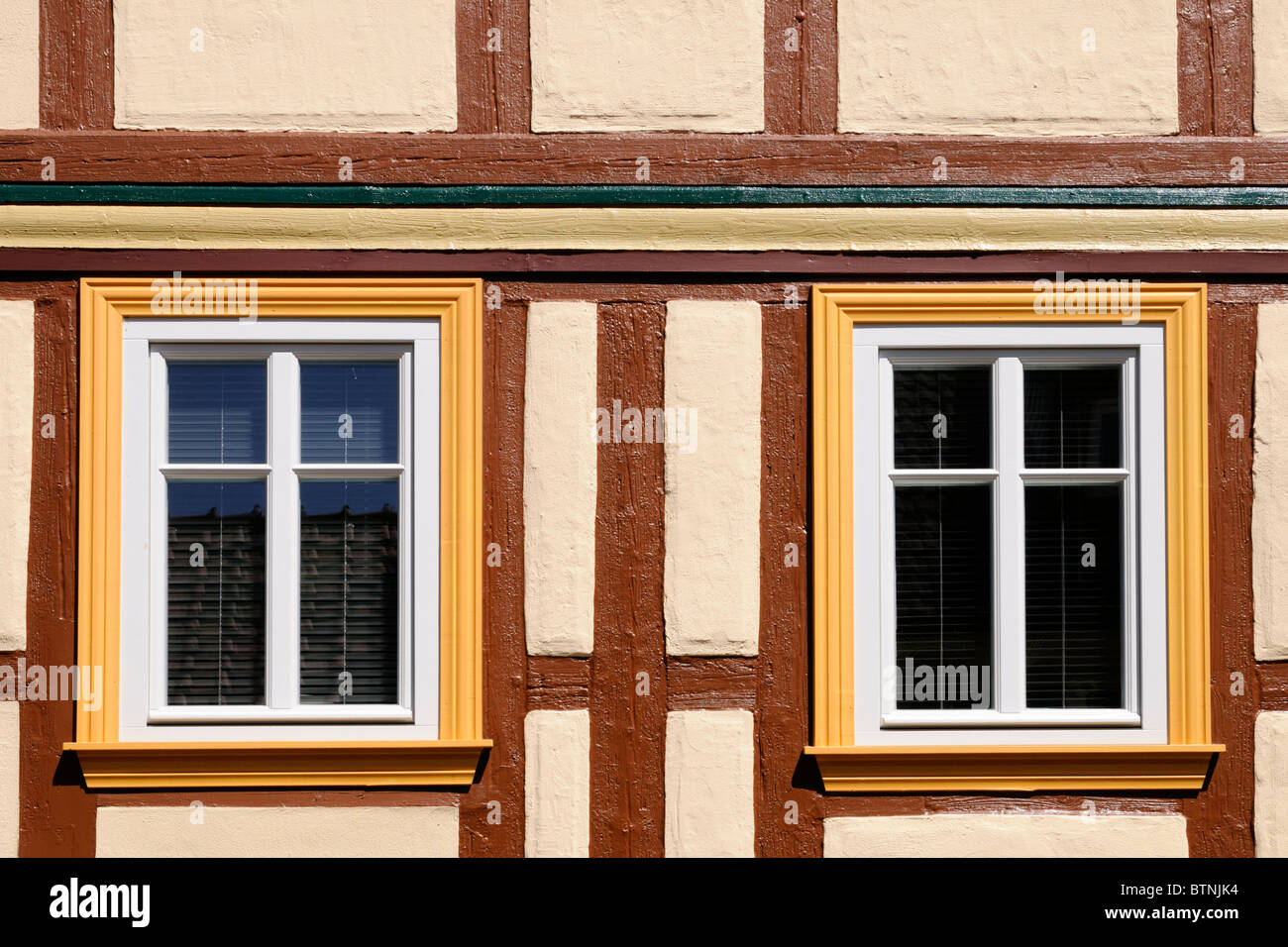 Fachwerkhaus mit Fenstern in gelb und weiß gestrichen. - Half-timbered house with windows painted in yellow and white. Stock Photo