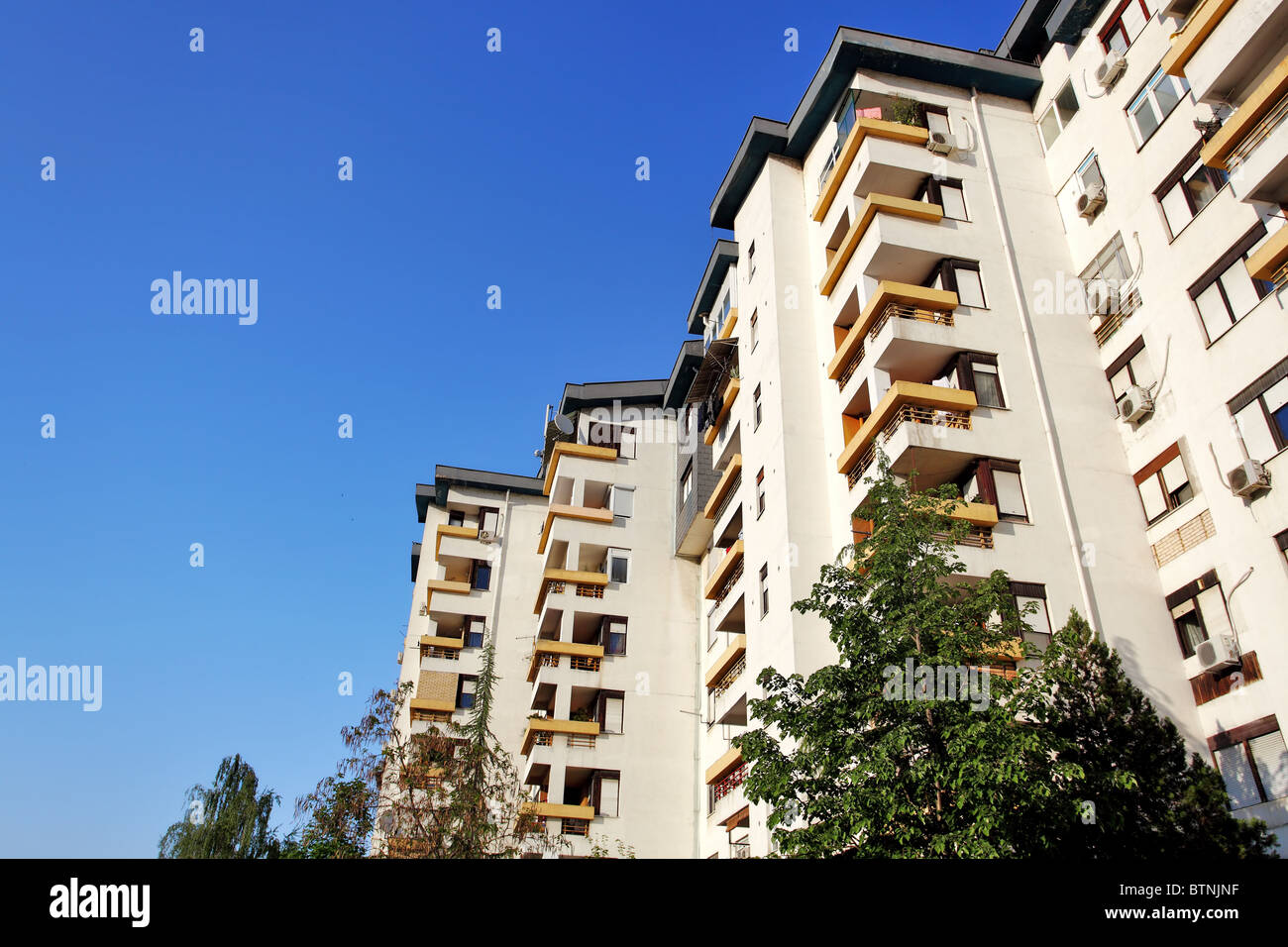 apartment complex with trees infront and blue sky Stock Photo